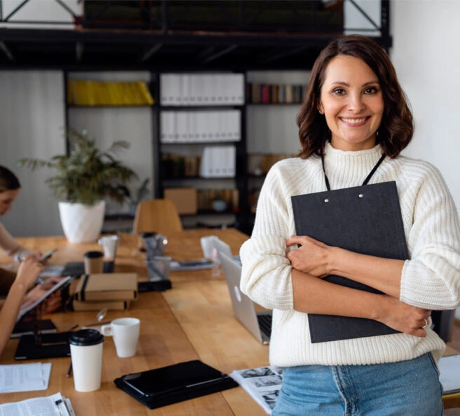 Smiling professional female accountant in a Dubai office holding a clipboard, representing expert bookkeeping firm