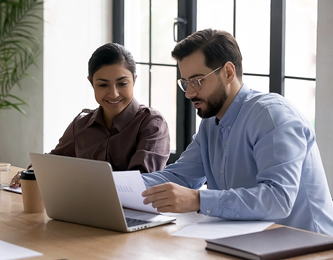 A smiling entrepreneur using a laptop and discussing bookkeeping and accounting firm in Dubai during a creative team meeting.